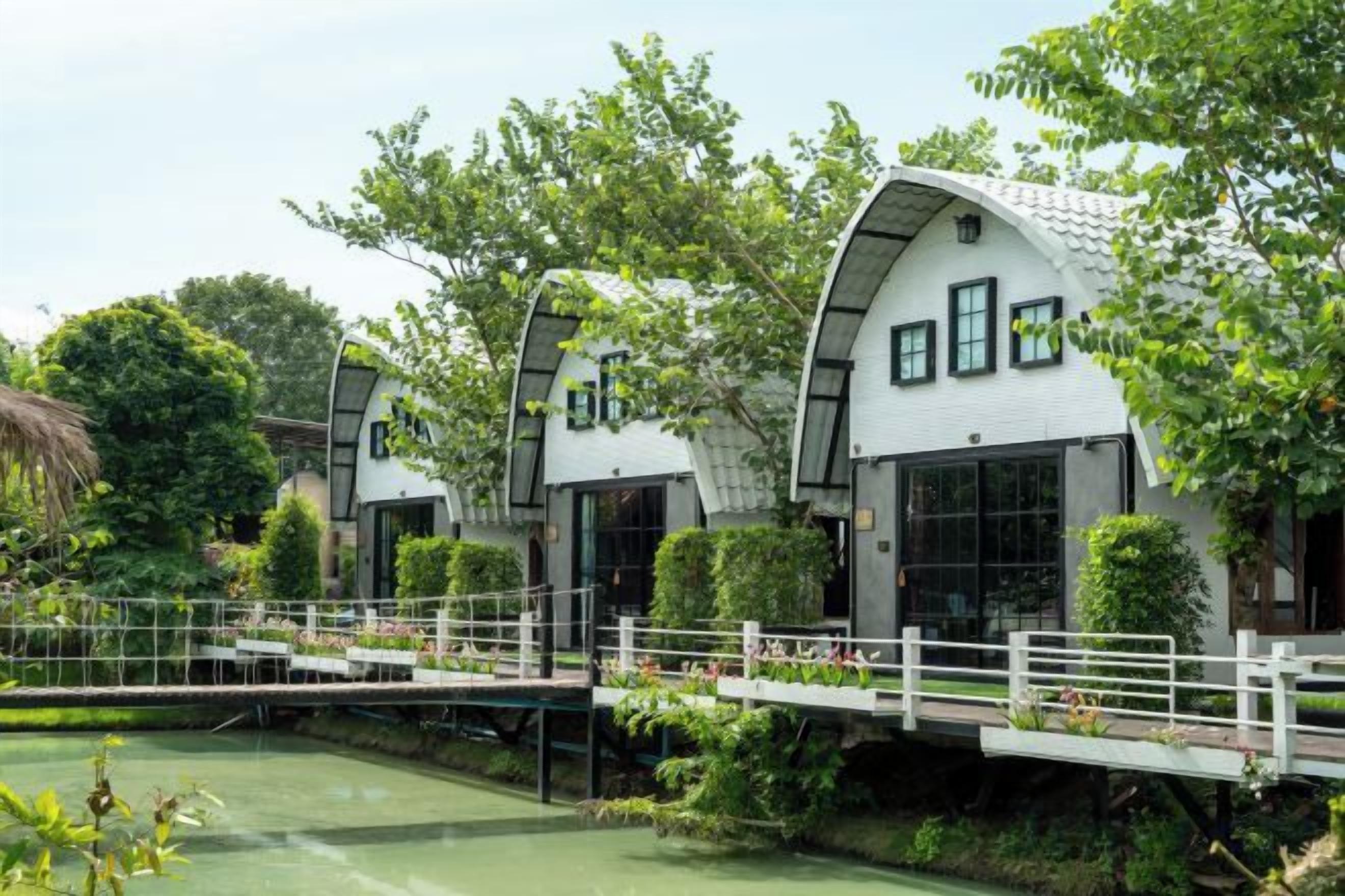 Una hilera de edificios blancos con techos curvos y ventanas amplias, un puente y una masa de agua.