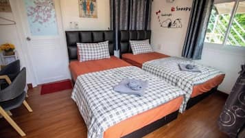 Un dormitorio con dos camas, una silla y un ventanal con cortinas.