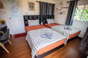 Un dormitorio con dos camas, una silla y un ventanal con cortinas.