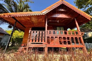 A wooden house with a balcony, surrounded by tall grass. - khao Thung Benja HomeStay (Phayuha Khiri)