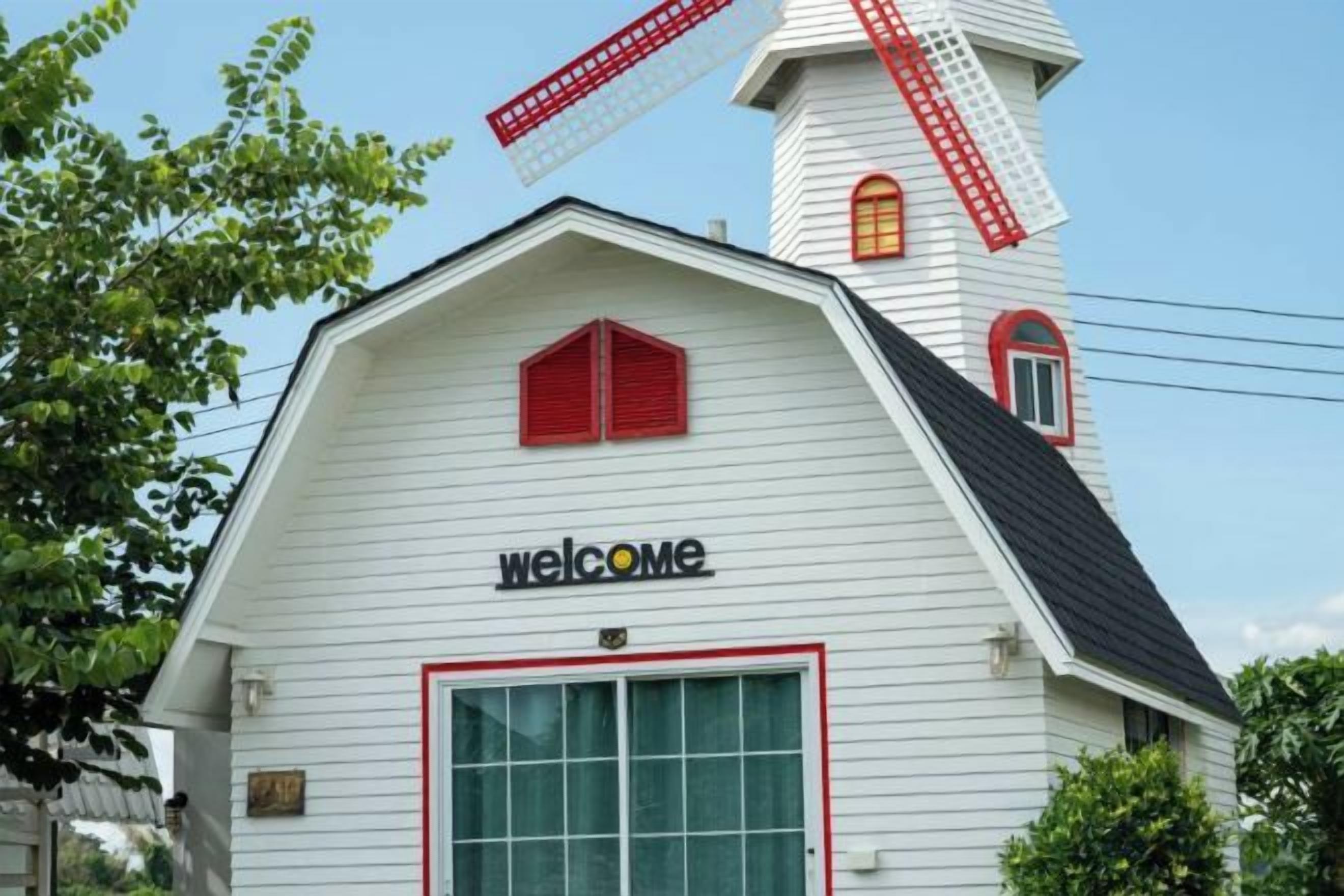 A white building with a red windmill and a 'welcome' sign.
