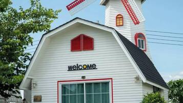 A white building with a red windmill and a 'welcome' sign.