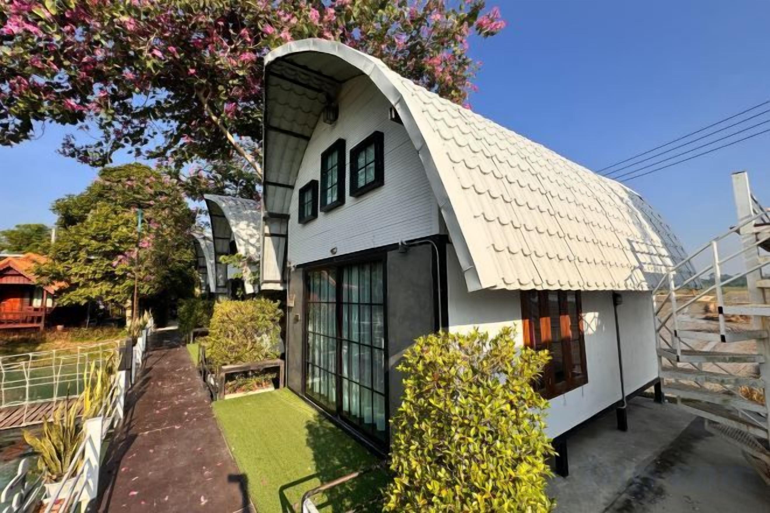 A modern house with a curved roof, large windows, and a small garden area.