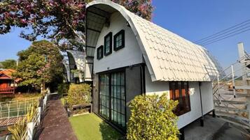A modern house with a curved roof, large windows, and a small garden area.