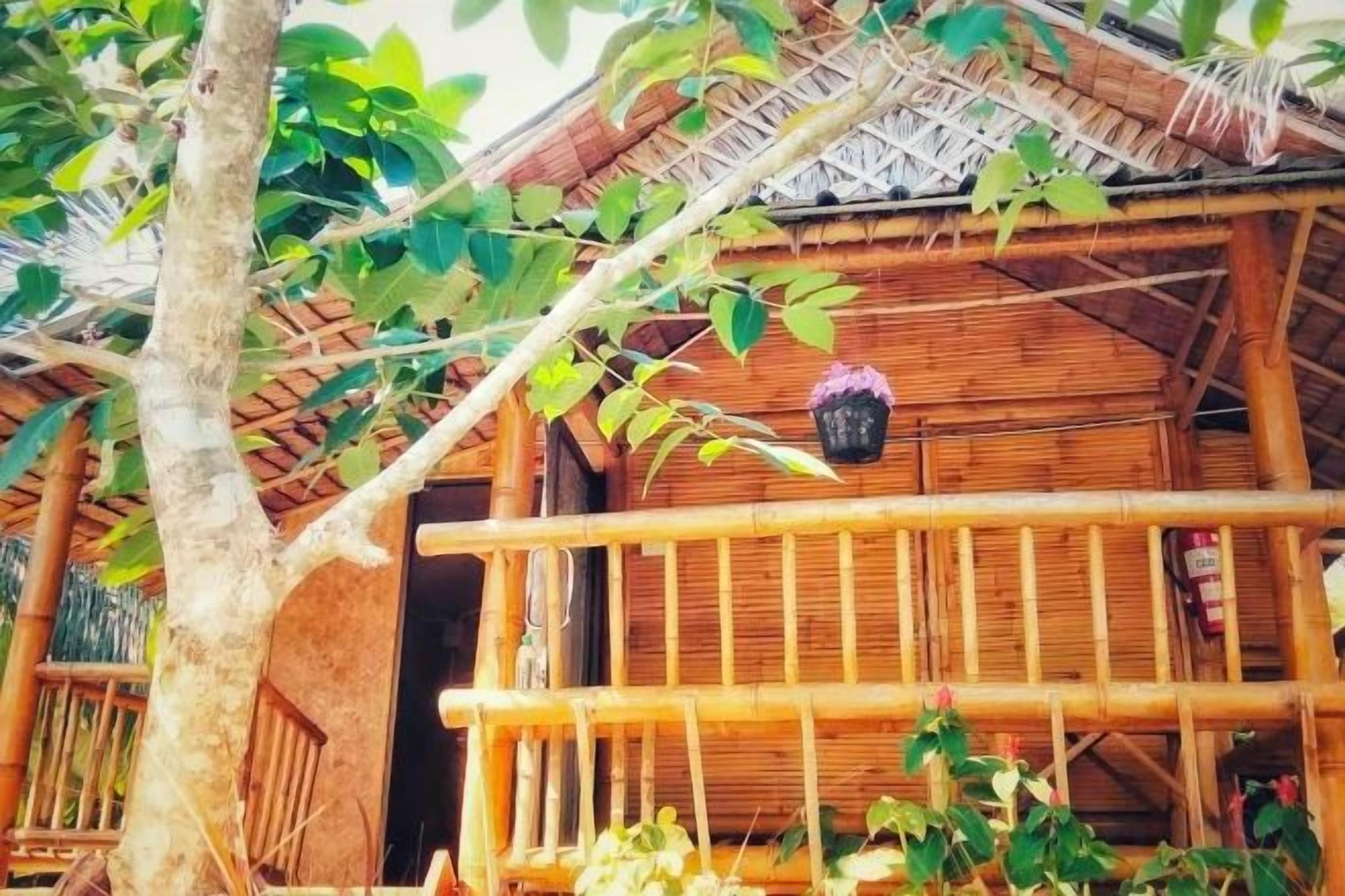 Un edificio de madera con balcón, techo de paja y maceta colgante.