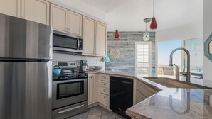 Una cucina moderna con elettrodomestici in acciaio inossidabile, mobili beige e un'ampia finestra con vista.