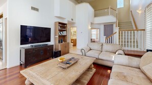 Un salón amplio con un televisor de pantalla plana grande, una mesa de centro de madera y un sofá beige.