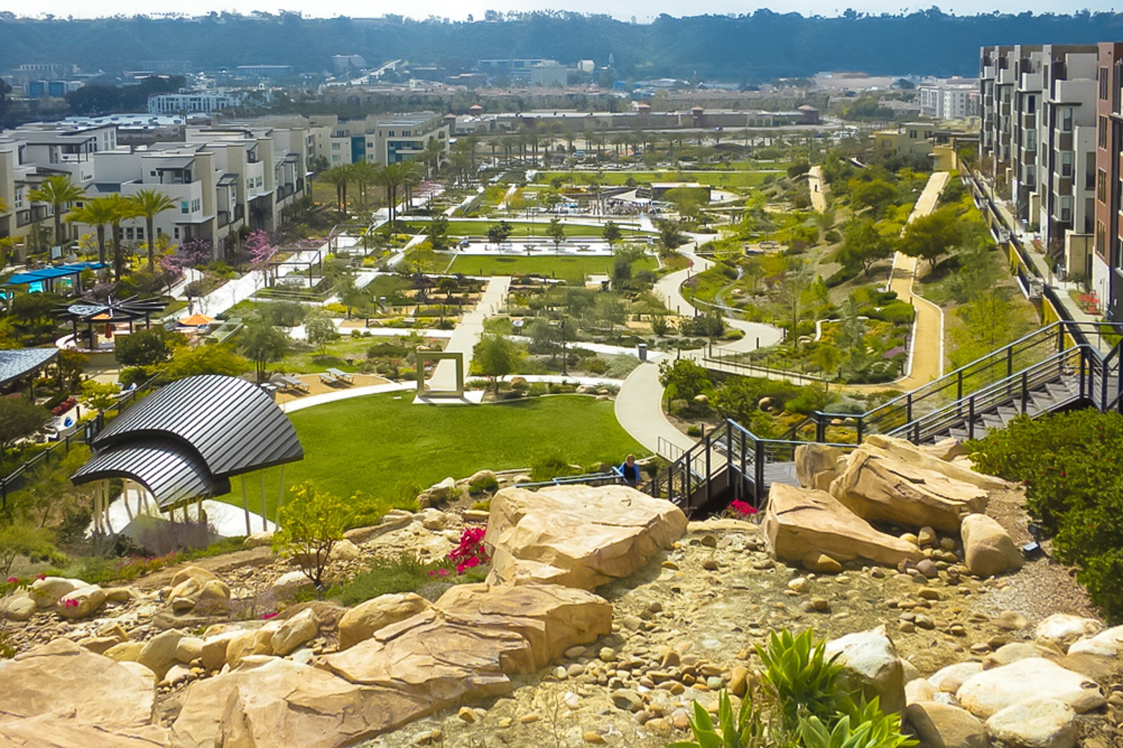 A landscaped garden with pathways, large rocks, and a small pavilion.