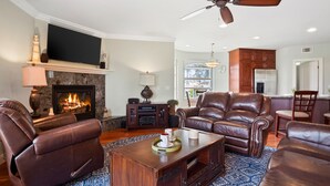 A spacious living room with leather sofas, a fireplace, and a television. - Buccaneer Beach Lookout - 30-Night Minimum (Oceanside)