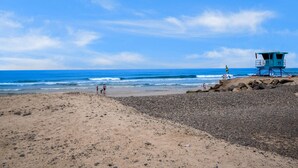A beach with a lifeguard tower, rocky shoreline, and clear blue sky. - Buccaneer Beach Lookout - 30-Night Minimum (Oceanside)