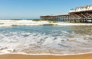 A wooden pier extending into the ocean with a building at the end.