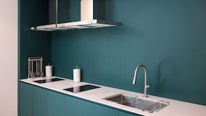 Eine moderne Küche mit dunkelblau gefliestem Fliesenspiegel, einer Edelstahl-Dunstabzugshaube und einem Waschbecken mit modernem Wasserhahn.