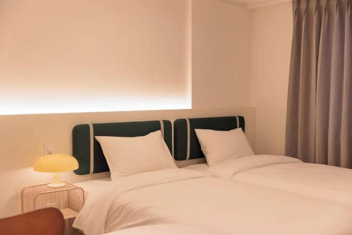 Une chambre d’hôtel avec un lit double, une lampe de chevet et un rideau.