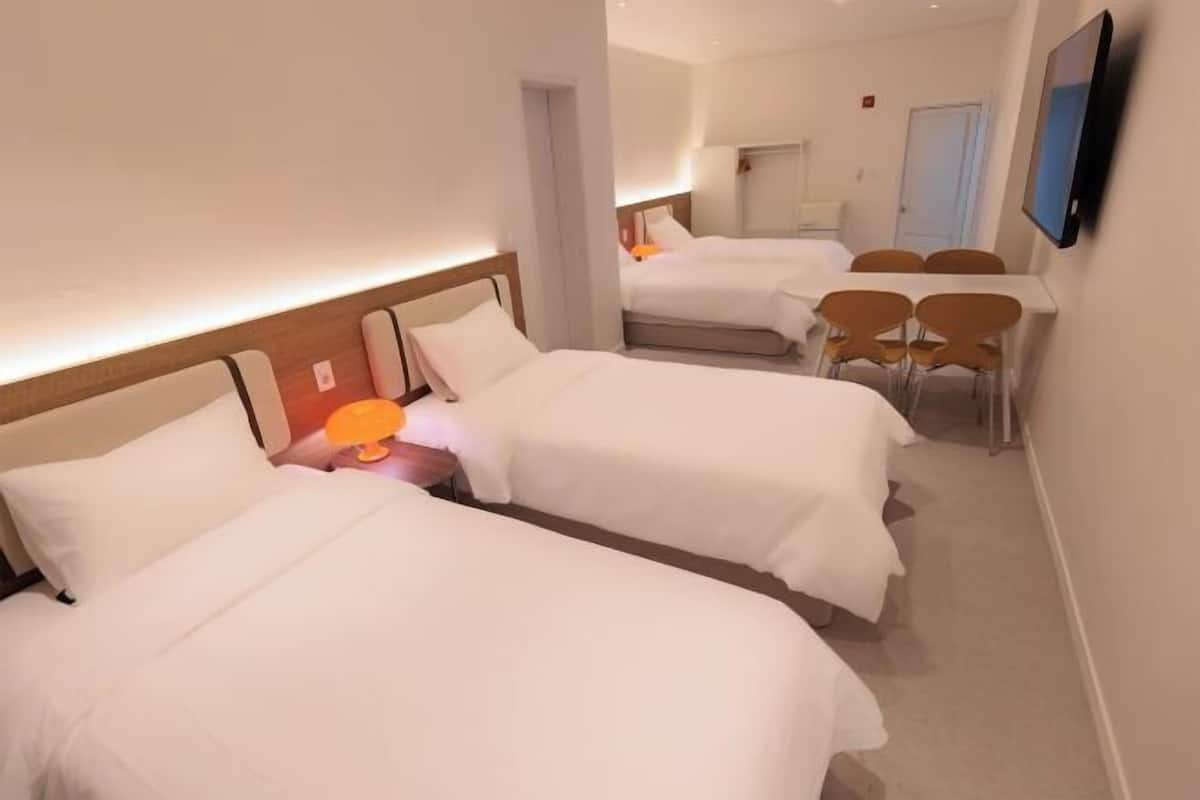 Une chambre d’hôtel avec deux lits, un bureau et une chaise.