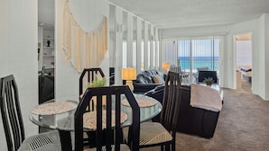 Una moderna camera d'albergo con zona pranzo, angolo relax e vista sull'oceano.