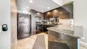A modern kitchen with stainless steel appliances, a granite countertop, and a backsplash. - Whitewater Village Charm - 30 Night Minimum (Oceanside)