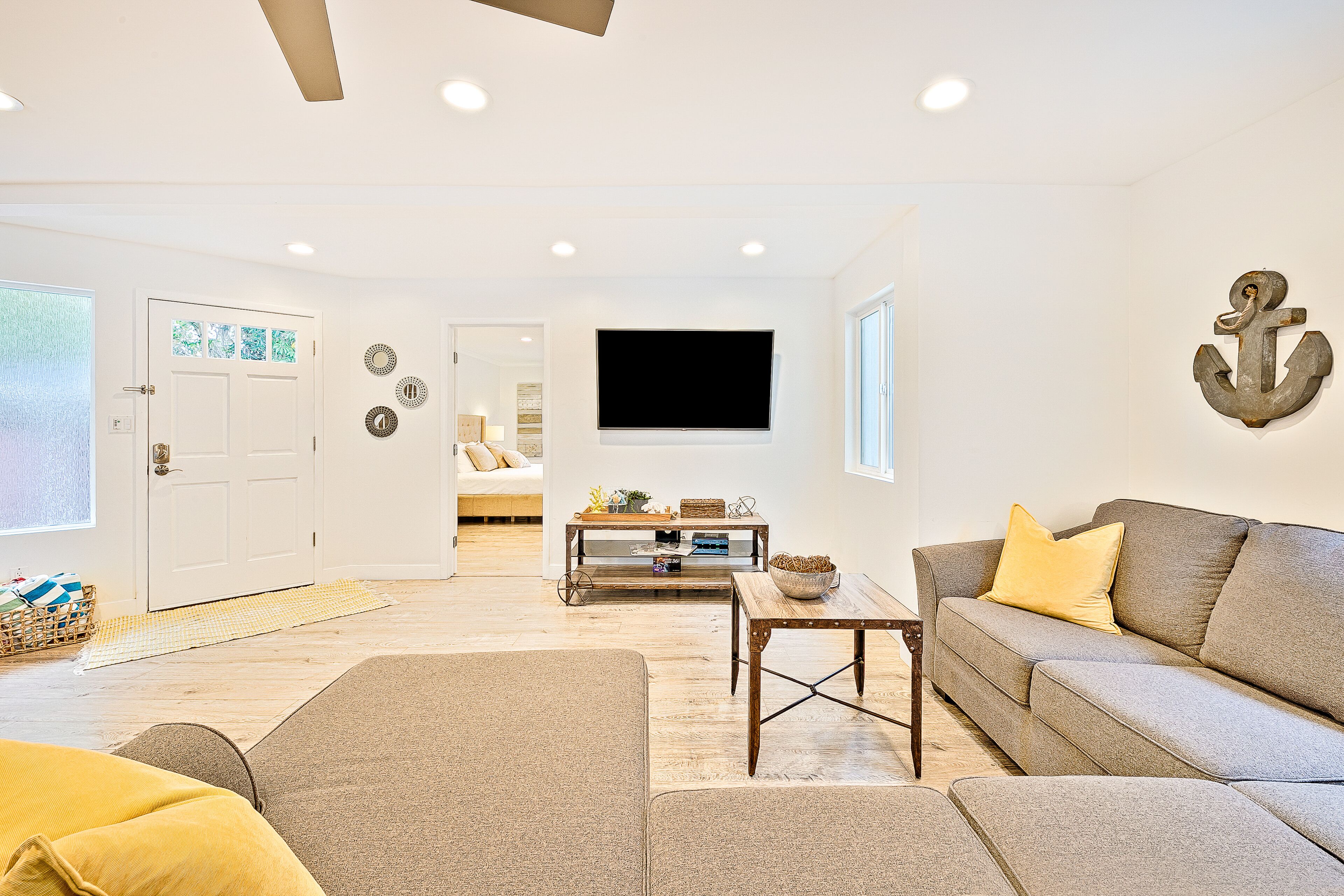 A living room with a sofa, coffee table, and a flat-screen TV mounted on the wall.