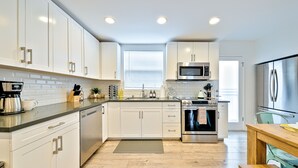 Una cocina moderna con armarios blancos, electrodomésticos de acero inoxidable y piso de madera.