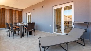Un espace patio moderne avec une table à manger pour quatre personnes, entouré de chaises en osier.