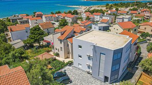 Un quartier résidentiel situé sur la côte, avec des immeubles modernes, une vue dégagée sur la mer et un espace de stationnement.