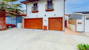 A two-story house with a garage, a balcony, and a palm tree. - Luxury Oceanfront Home - Lower (Oceanside)