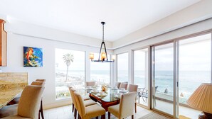 A dining area with a glass table, chairs, and a view of the ocean. - Luxury Oceanfront Home - Lower (Oceanside)