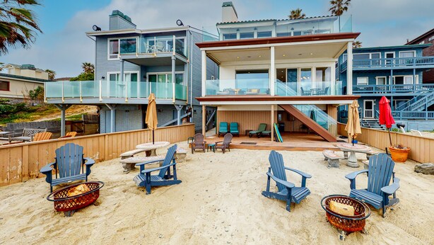 A beachfront property with multiple levels, outdoor seating, and a fire pit area. - Luxury Oceanfront Home - Lower (Oceanside)