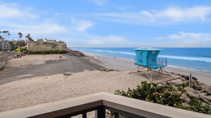 A beach with a lifeguard tower, a sandy area, and buildings in the background.
