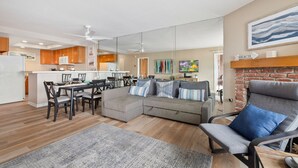 A modern living room with a sectional sofa, a dining area, and a kitchen in the background.