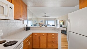 A modern kitchen with wooden cabinets, white countertops, and a built-in microwave.