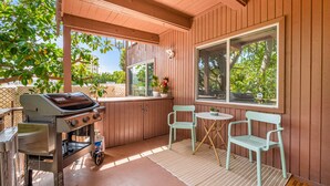 Un patio couvert avec un barbecue, deux chaises et une table.