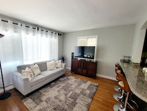 A living room with a sofa, TV, and a bar area. - Playa Del Sur Getaway La Jolla (La Jolla)