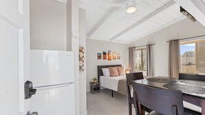 A modern bedroom with a bed, bedside table, and a view of the outside. - Sweet Sunset Studio Charming Condo (San Diego)