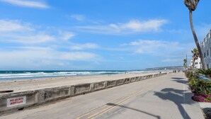 A coastal road with a 'NO GLASS BOTTLES' sign, a beach, and a clear blue sky. - Sweet Sunset Studio Charming Condo (San Diego)