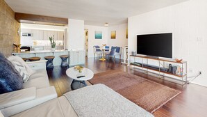 Ein modernes Wohnzimmer mit einer Couch, einem Couchtisch und einem Fernseher auf einem Schrank.