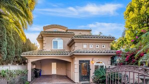 Een huis in mediterrane stijl met een pannendak, een overdekte oprit en een hekpoort.