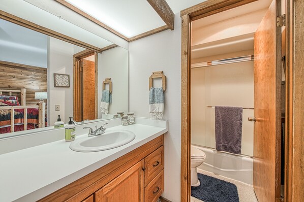 Une salle de bain avec un meuble-lavabo en bois, un grand miroir et un espace douche.