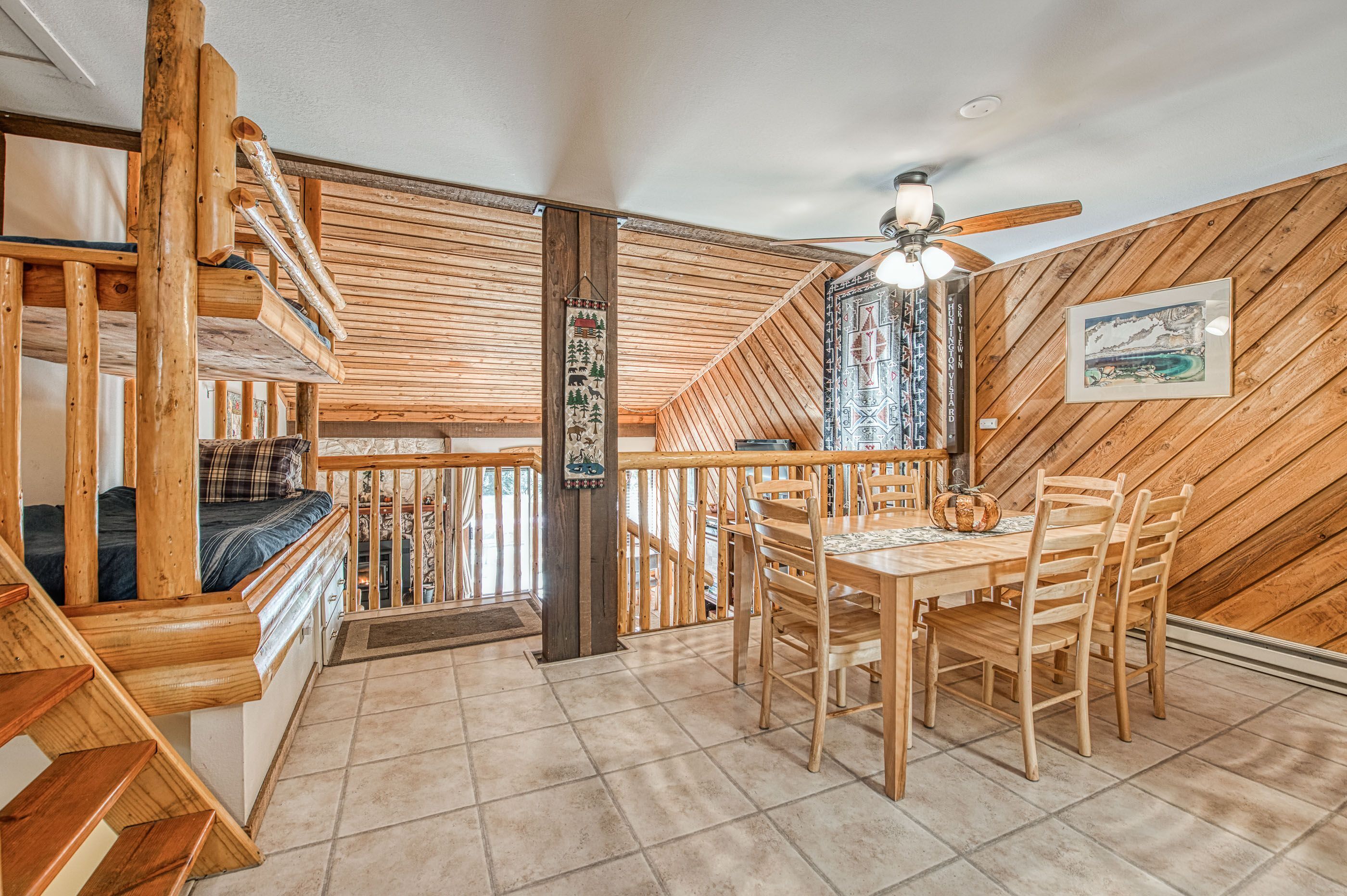 A wooden interior with a dining area, staircase, and a ceiling fan.