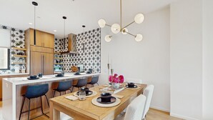 Uma cozinha moderna com ilha de madeira, banquetas e uma mesa de jantar para quatro pessoas.
