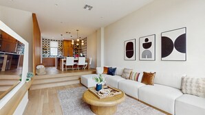 Uma sala de estar moderna com um sofá branco, uma mesa de centro de madeira e arte abstrata nas paredes.