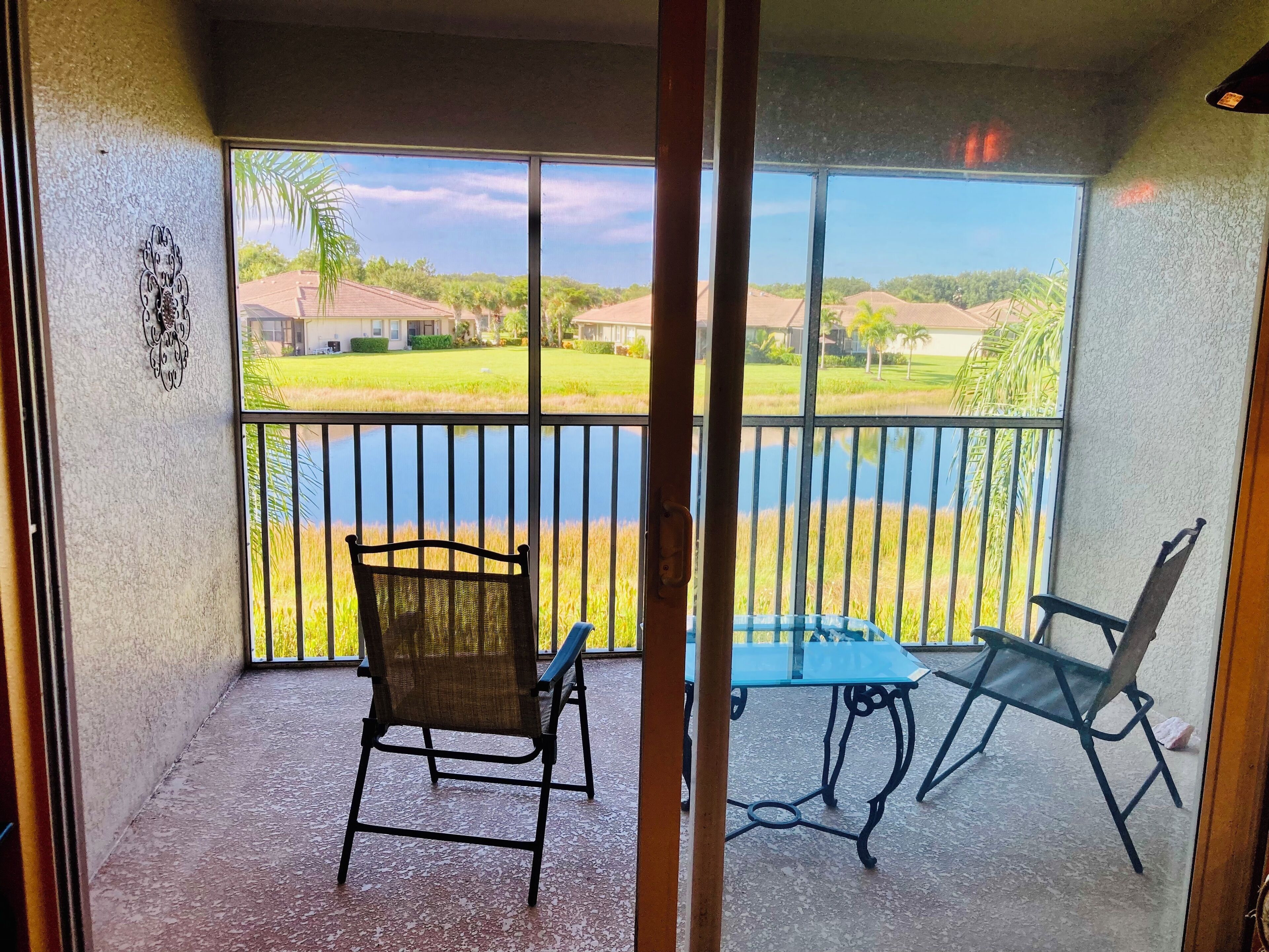 Un balcon donnant sur un lac et des maisons, aménagé avec une chaise et une table.