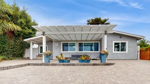 Ein modernes Haus mit überdachter Terrasse, großen Fenstern und Kübelpflanzen.