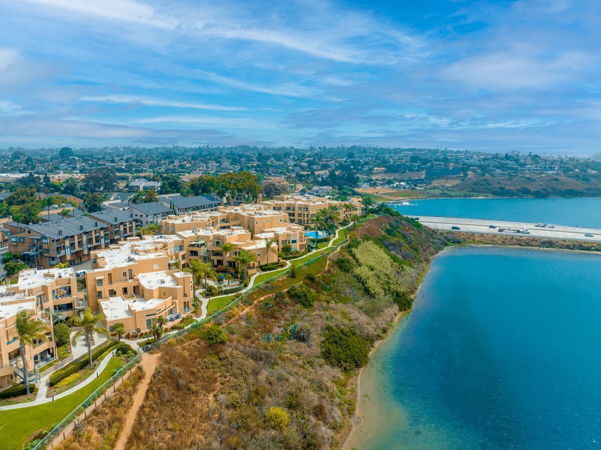Zona residencial costera con modernos edificios de apartamentos, una playa y una autopista al fondo.