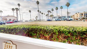 Vista sulla spiaggia con palme, un parcheggio e edifici sullo sfondo.