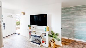 Un soggiorno moderno con una televisione a schermo piatto, un camino e un mobile TV bianco.
