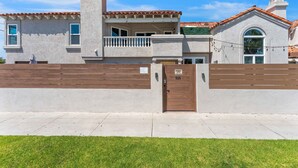 Una casa a due piani con un balcone, un garage e un prato curato.