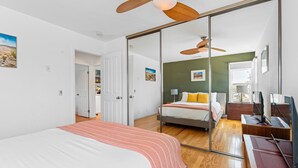 Una camera da letto con un letto, una scrivania, una sedia, un armadio e una porta scorrevole che dà su un'altra stanza.