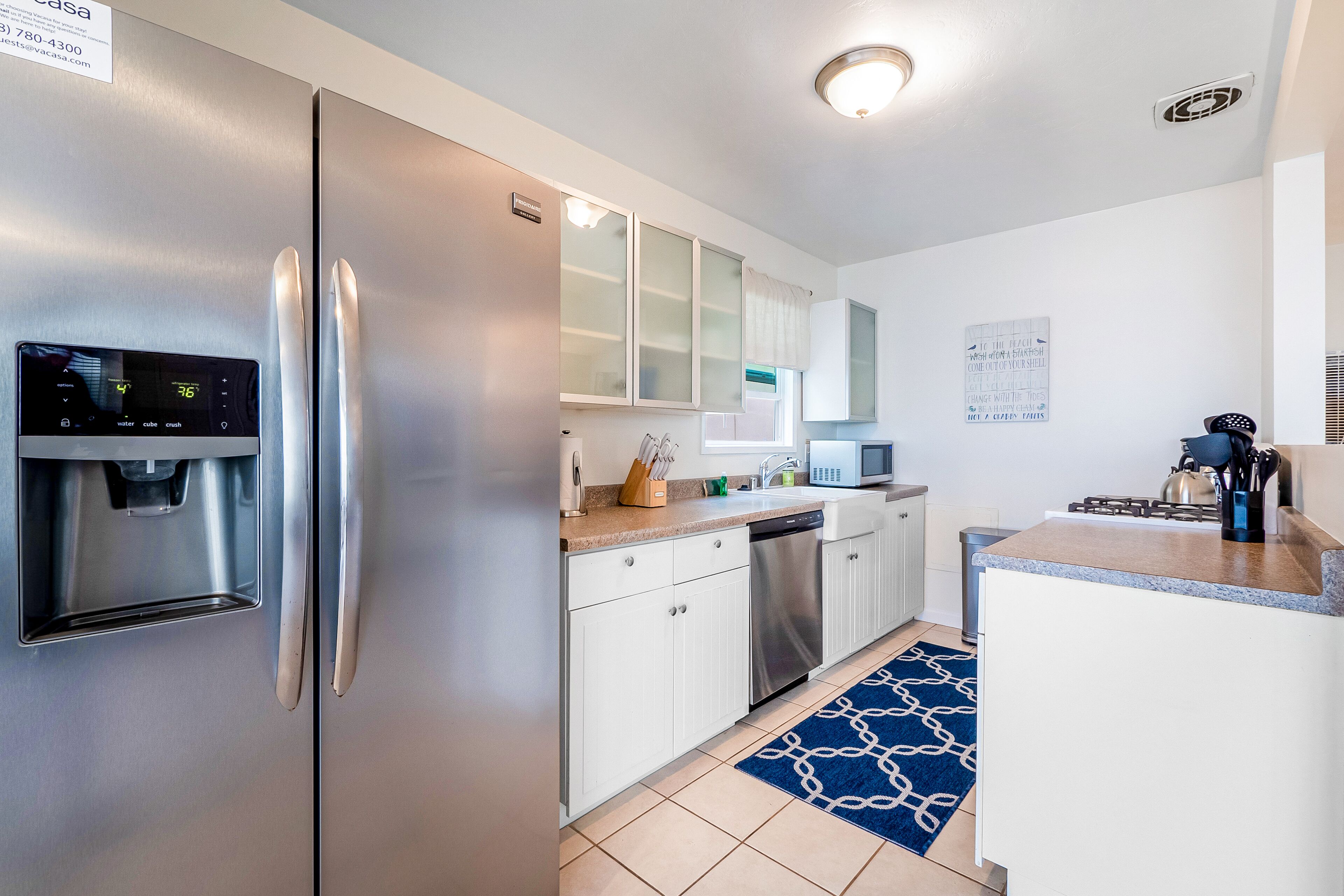 A compact kitchen with a refrigerator, water dispenser, microwave, and a sink.