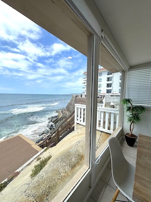 A balcony with a view of the ocean and a building across the street.