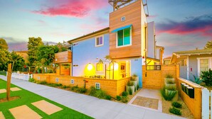 Una casa moderna a due piani con facciata in legno, un balcone e un giardino curato.